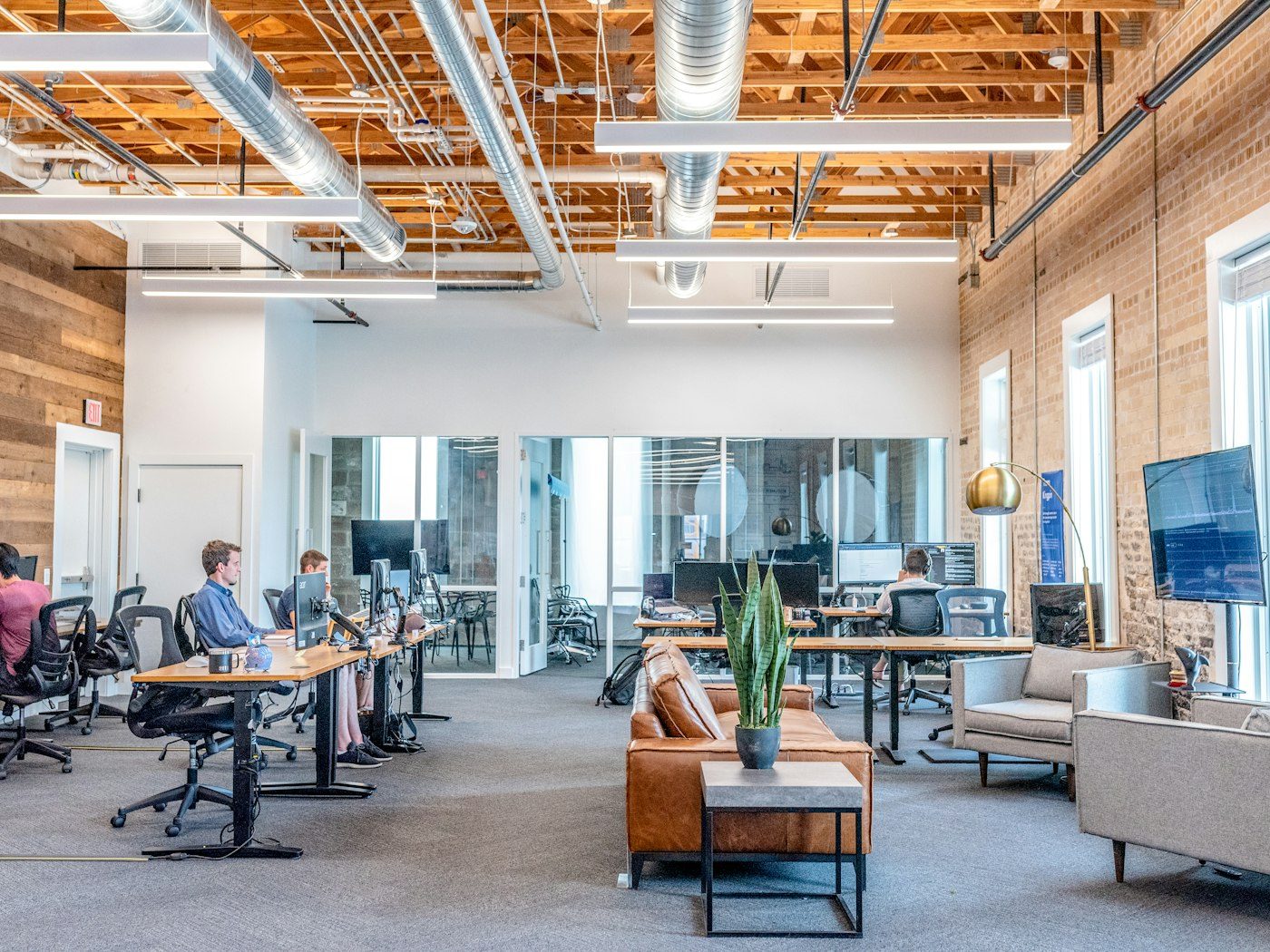Open-plan office with exposed ceiling, glass meeting rooms and staff at their desks